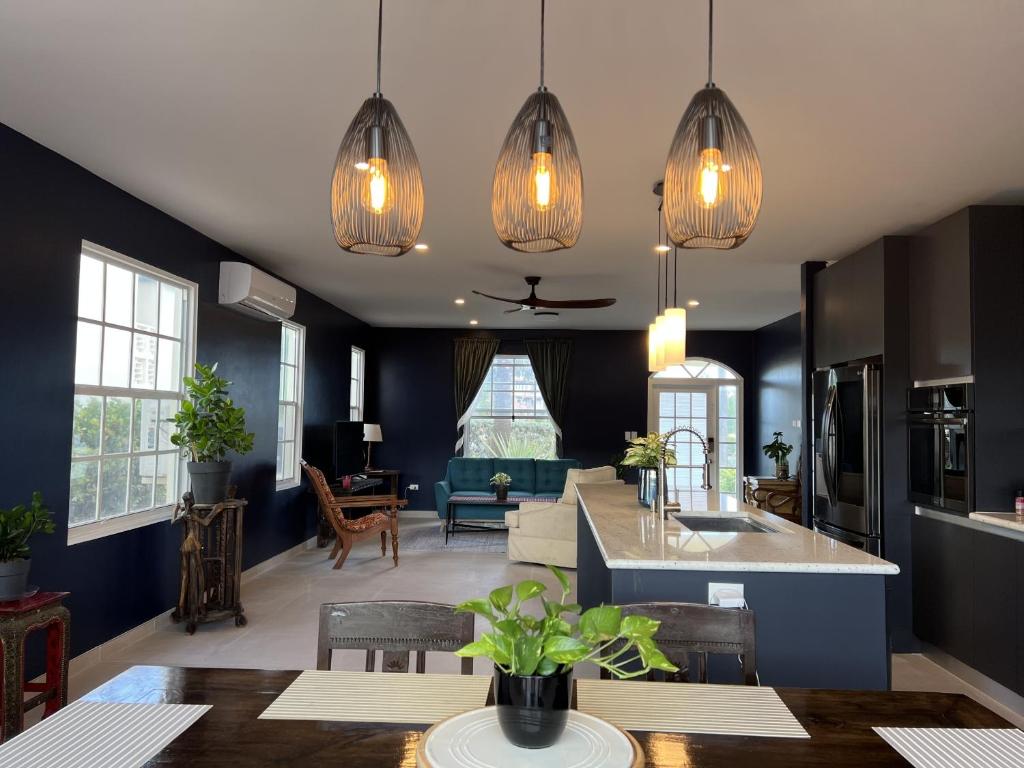 a kitchen and living room with blue walls and pendant lights at Sea Winds Bungalow - Tierra Del Sol Aruba in Noord