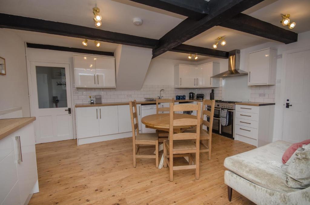 a kitchen with white cabinets and a table and chairs at Hideaway Cottage in Bristol