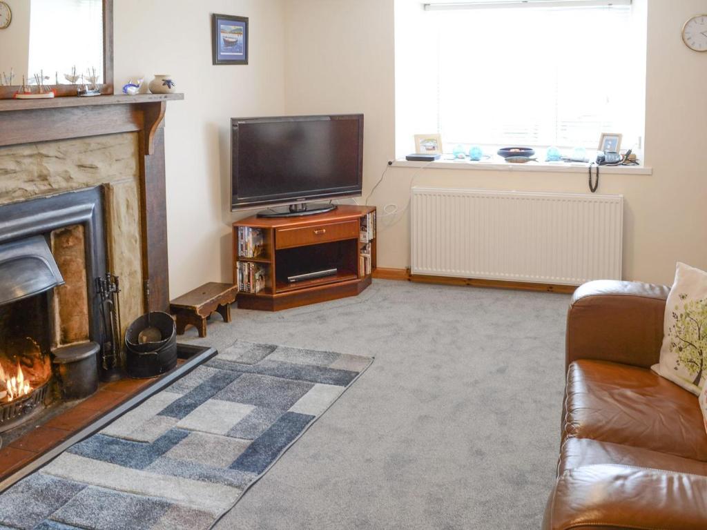 a living room with a fireplace and a television at Shore Cottage in Rockfield