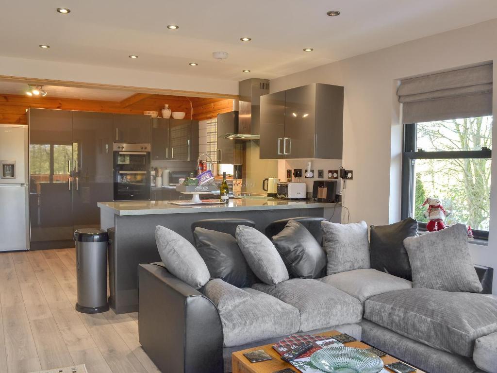 a living room with a couch and a kitchen at Quarry Lodge in Little Marcle