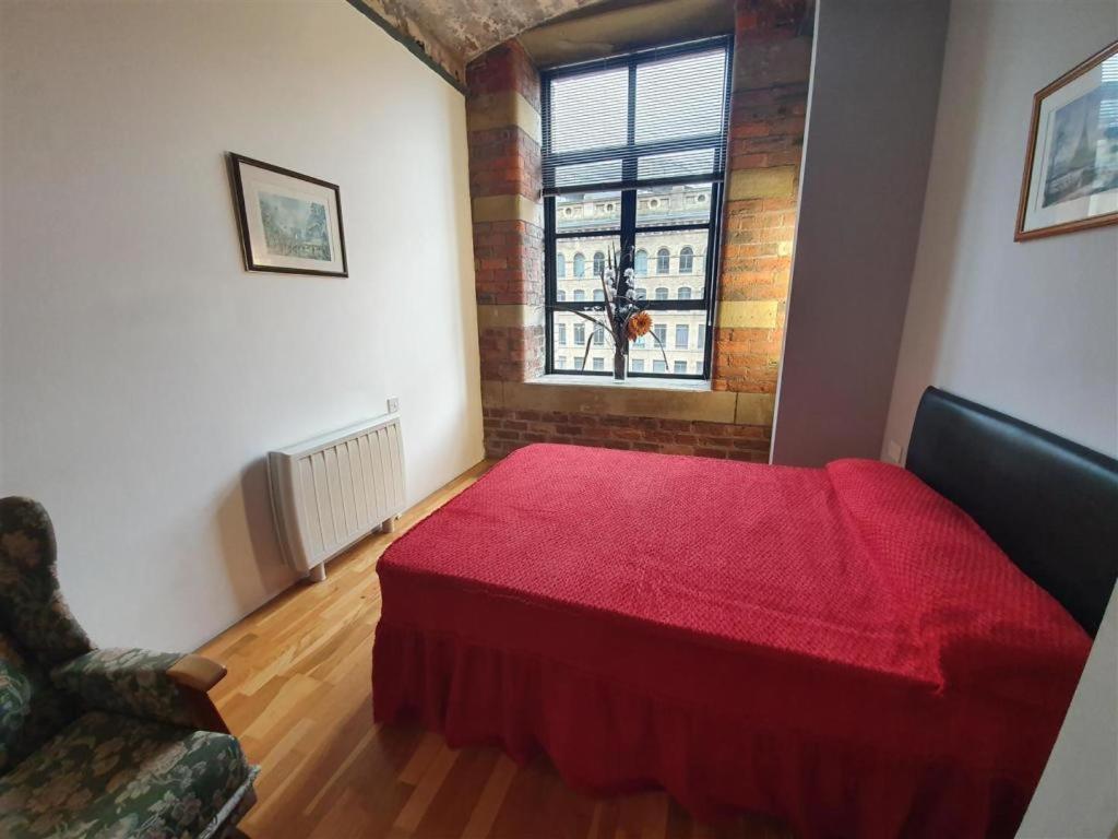 1 dormitorio con cama roja y ventana en Lister Mills, Apartment 327, Silk Warehouse, Lilycroft Rd, BD9 5BD en Bradford