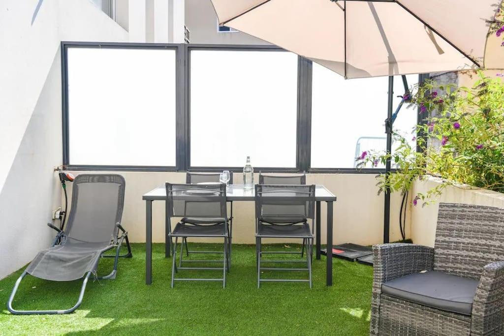 a table and chairs in a room with green grass at Le Capé-Grand appartement avec terrasse et jacuzzi in Marseille
