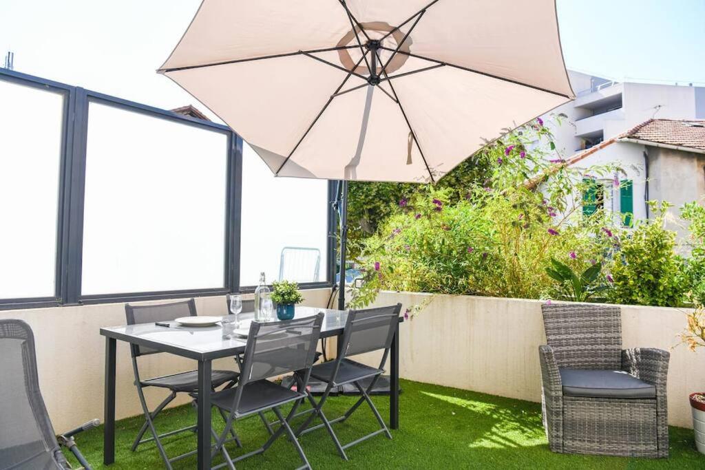 a table and chairs with an umbrella on a patio at Le Capé-Grand appartement avec terrasse et jacuzzi in Marseille