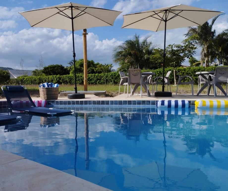 a swimming pool with chairs and umbrellas at Casa com piscina aquecida, privativa,diarista, em condomínio, Bonito-Pe in Bonito