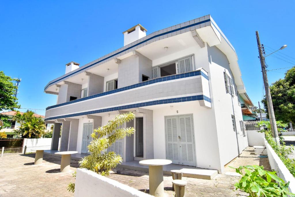Una casa blanca con una raya azul. en Meia quadra da Praia nos Ingleses, 4 hóspedes P2057, en Florianópolis