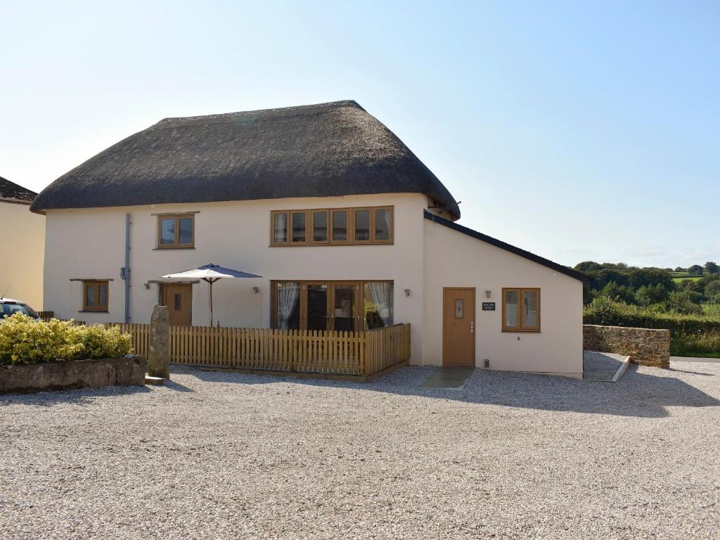 a large white house with a thatched roof at South Barn in Monk Okehampton