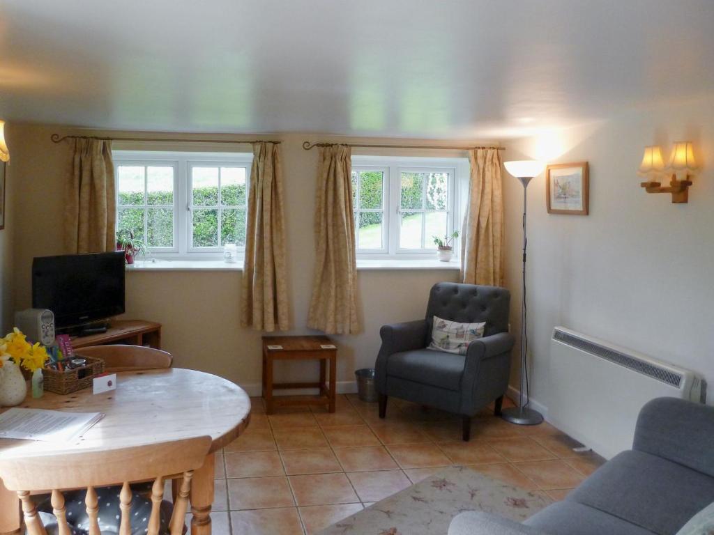 a living room with a table and a chair at Wren Cottage in Netherbury