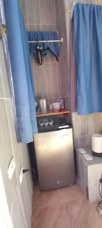 a small kitchen with a blue curtain in a room at chambre indépendante chez l'habitant in Parrita