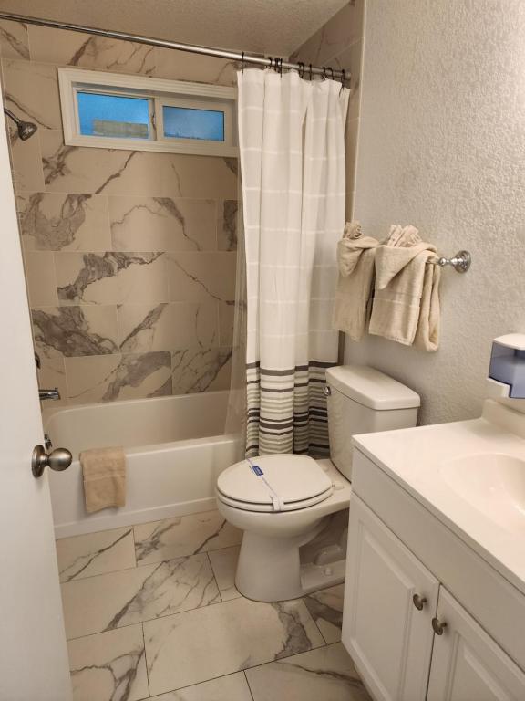 a bathroom with a toilet and a sink and a shower at Plainview Motel in Coos Bay