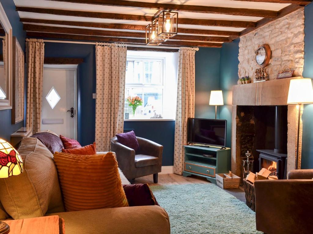 a living room with a couch and a fireplace at Parsley Cottage in Tideswell