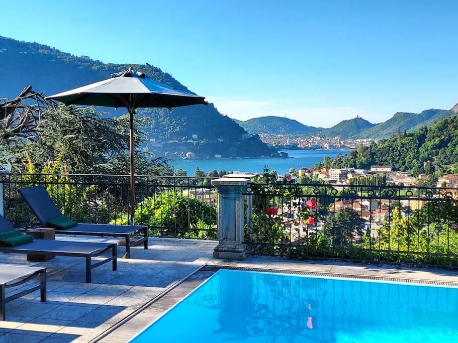a pool with an umbrella and a view of the water at Casa Santo Stefano in Cernobbio