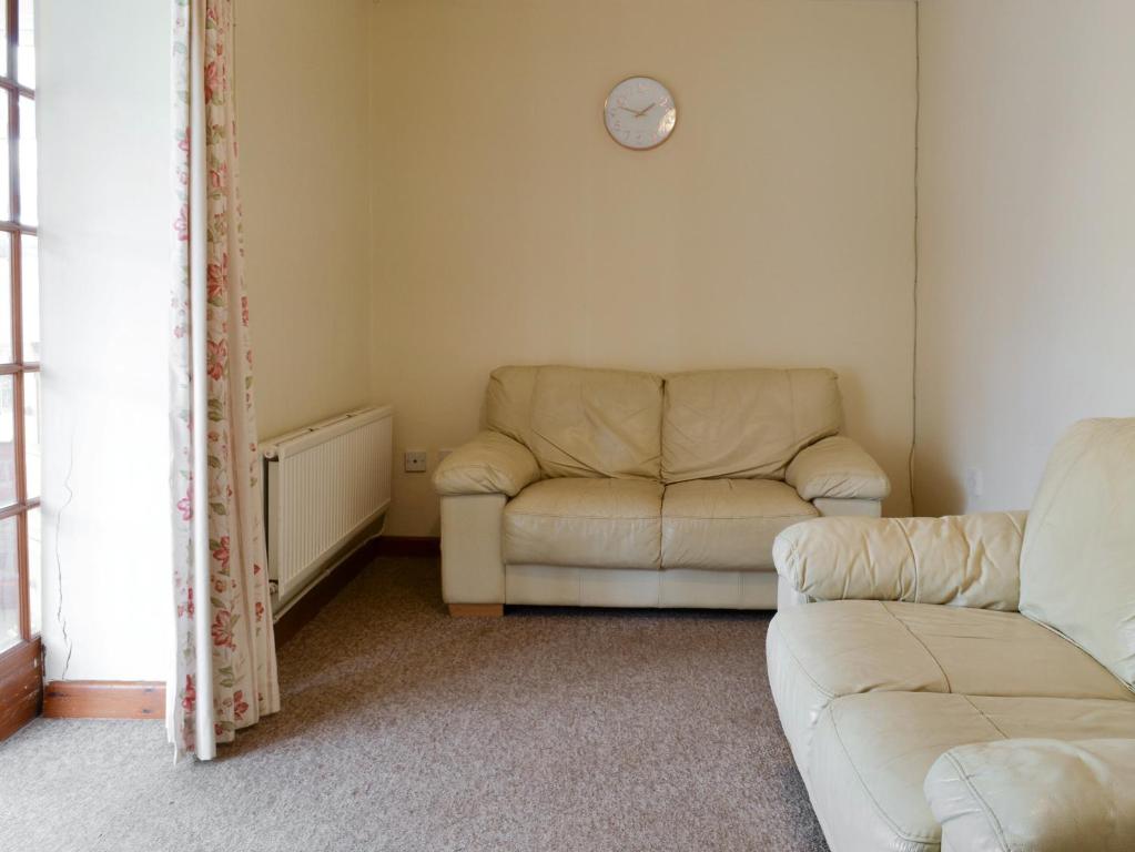 a living room with a couch and a clock on the wall at Stable Cottage 3 - Ukc3742 in Bawdeswell