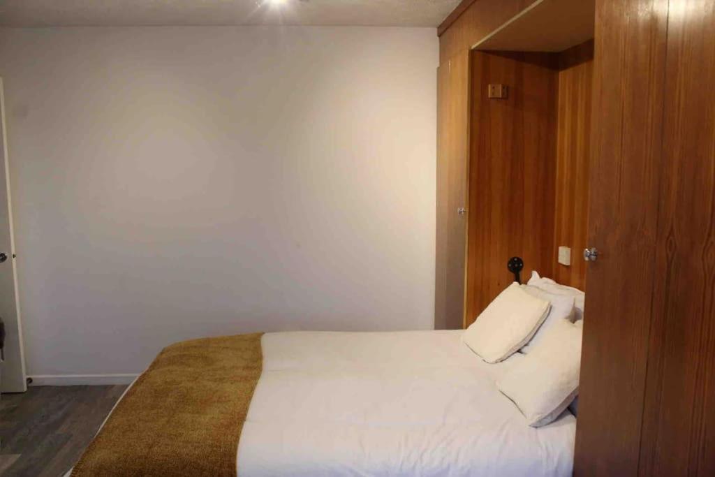 um quarto com uma cama branca e uma porta de madeira em Modern studio apartment with parking em Chatham