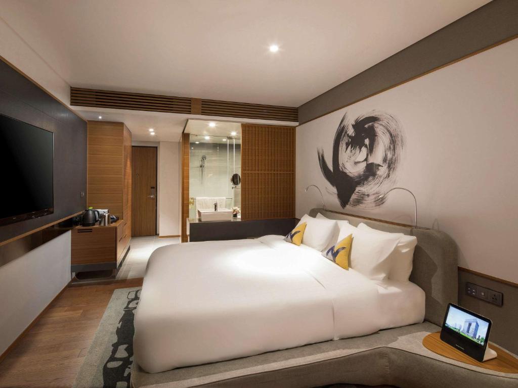 una camera da letto con un grande letto bianco e una televisione di Novotel Ambassador Seoul Dongdaemun Hotels & Residences a Seul