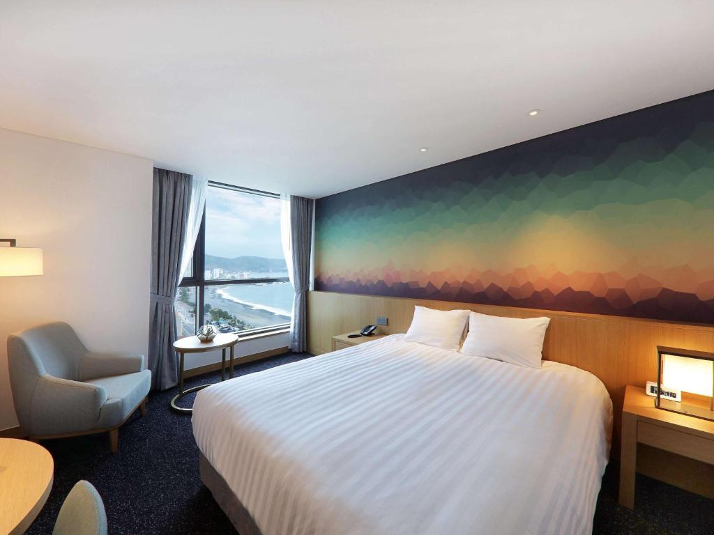 a hotel room with a bed and a large window at Mercure Ambassador Ulsan in Ulsan