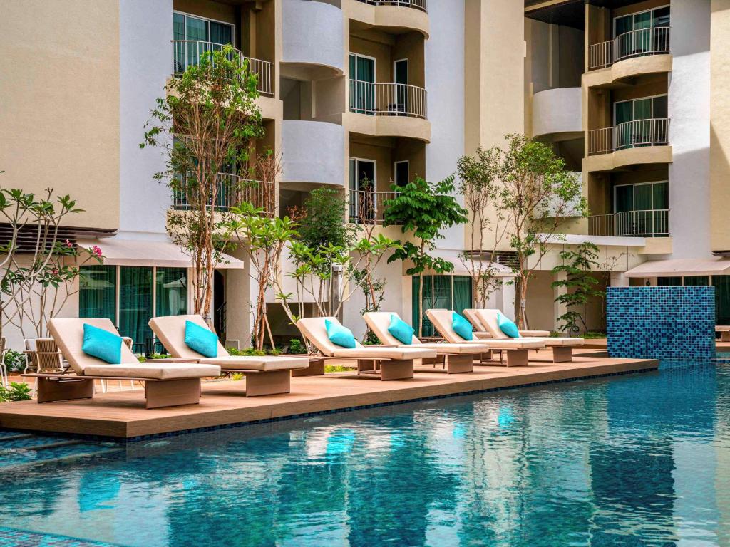 a hotel swimming pool with lounge chairs in front of a building at Mercure Langkawi Pantai Cenang in Pantai Cenang