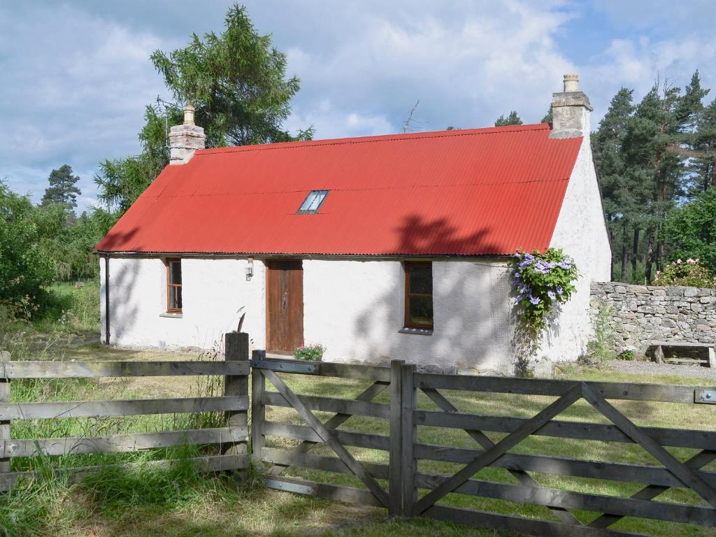 a small house with a red roof and a fence at St Orans in Rafford
