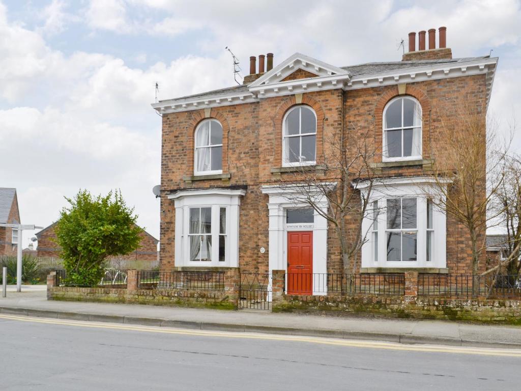 a brick house with a red door on a street at Station House in Hornsea