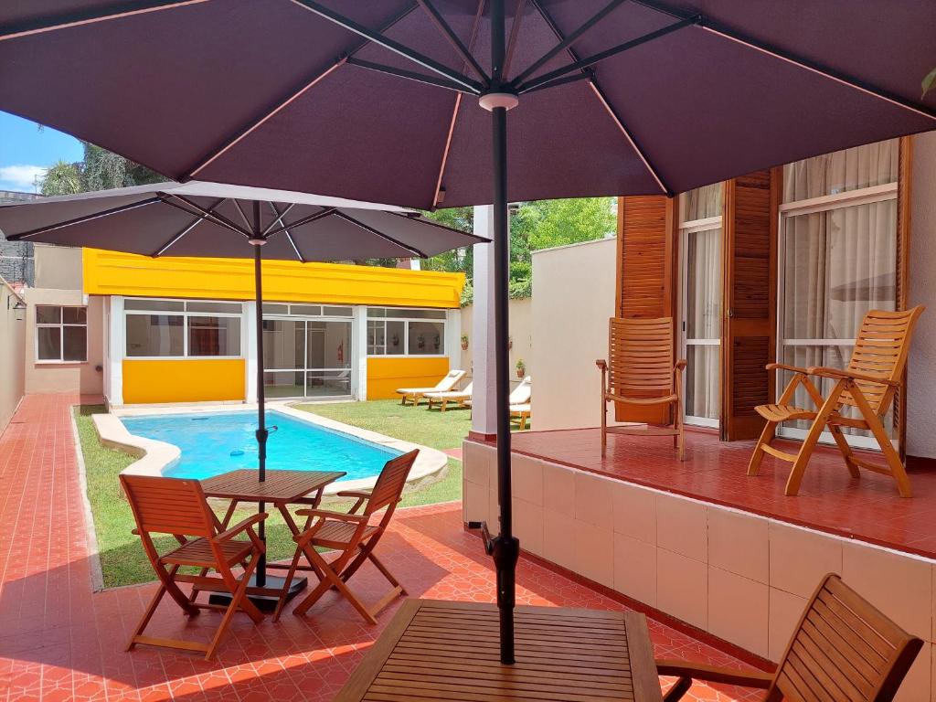 a patio with a table and chairs and an umbrella at La Casa del Parque B&B in Mendoza