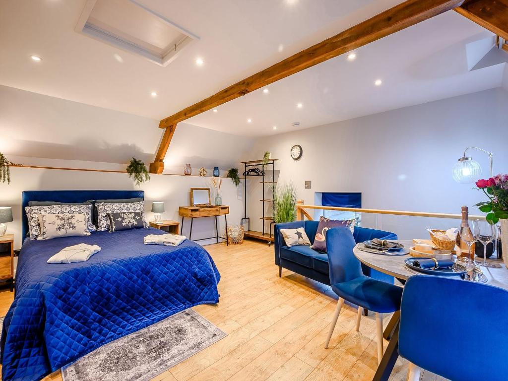 a bedroom with a blue bed and a blue couch at Dassett View in Fenny Compton