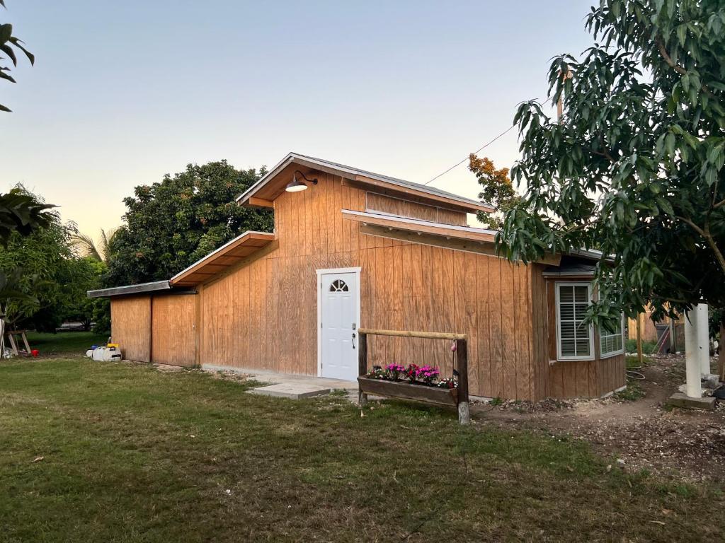 een klein houten gebouw met een witte deur bij Maria's Tiny Barn in Homestead