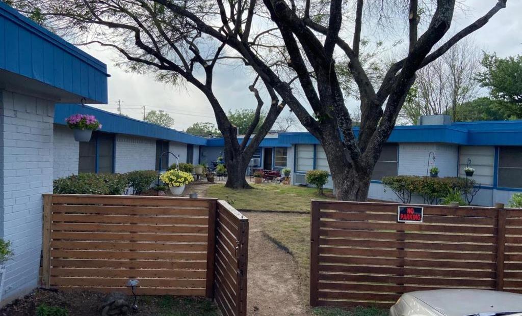 a wooden fence in front of a house with a tree at La Unica in Austin
