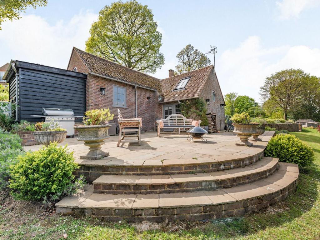 a patio with steps leading to a house at The Cottage High Wykehurst End in Cranleigh