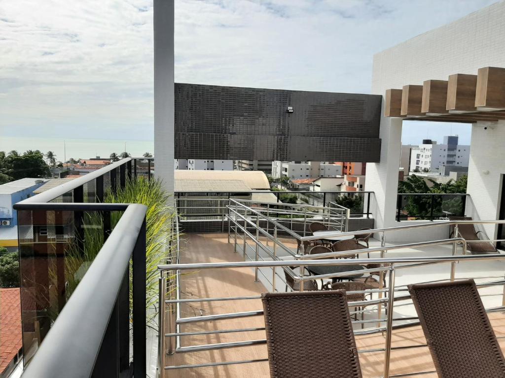 Un balcón con sillas y mesas en un edificio en Maravilhoso apto no Bessa, en João Pessoa