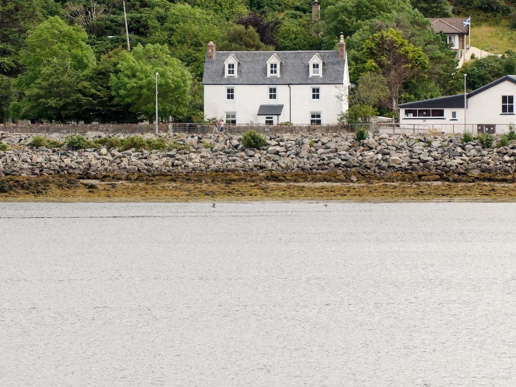 a white house on the shore of a body of water at Seafield House in Lochinver