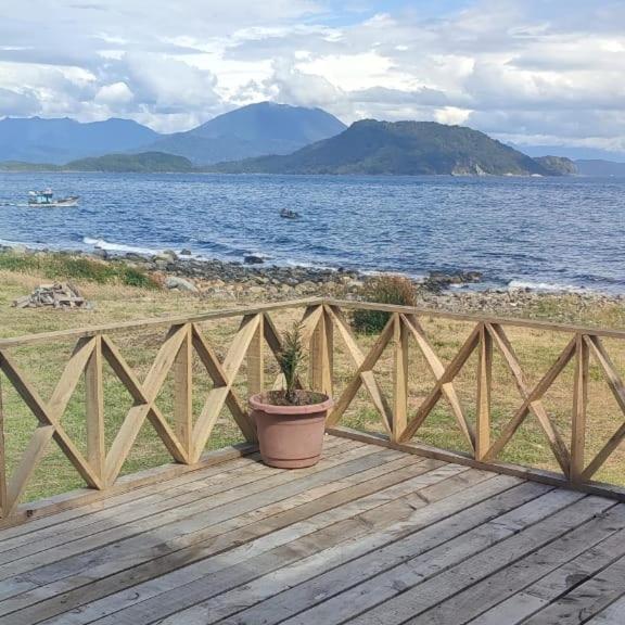 una maceta sentada en una terraza de madera cerca del océano en Refugio Hualaihue, en Hornopirén