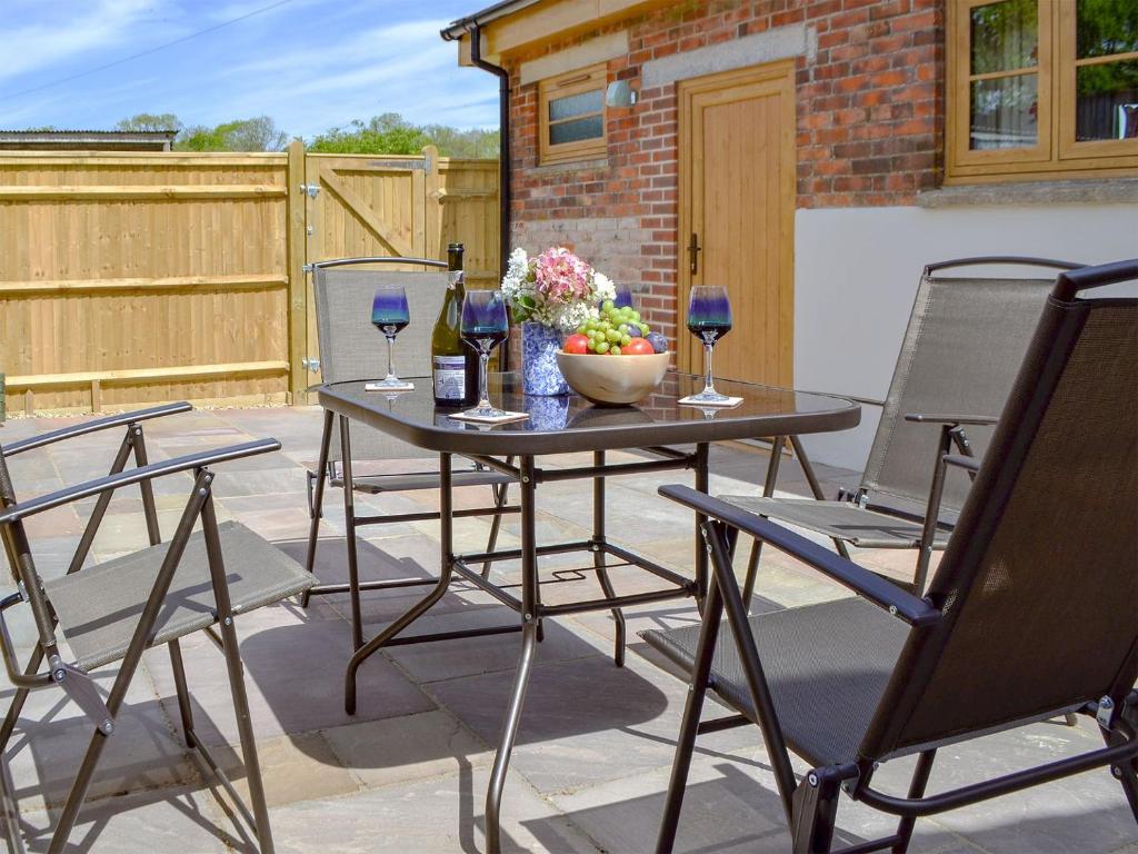 a patio table with two chairs and wine glasses at Woodlands Dairy Cottage in Billingshurst