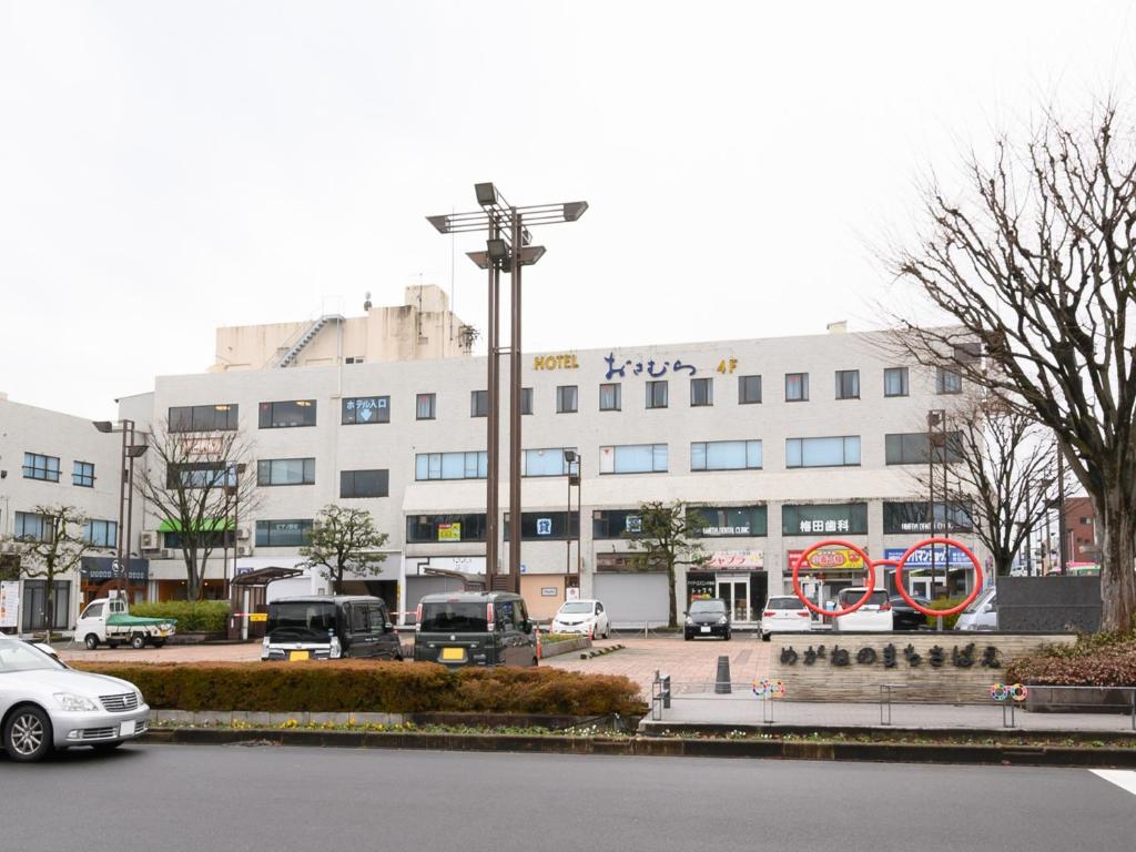 ein großes Gebäude mit Autos auf einem Parkplatz in der Unterkunft Tabist Business Hotel Osamura in Sabae