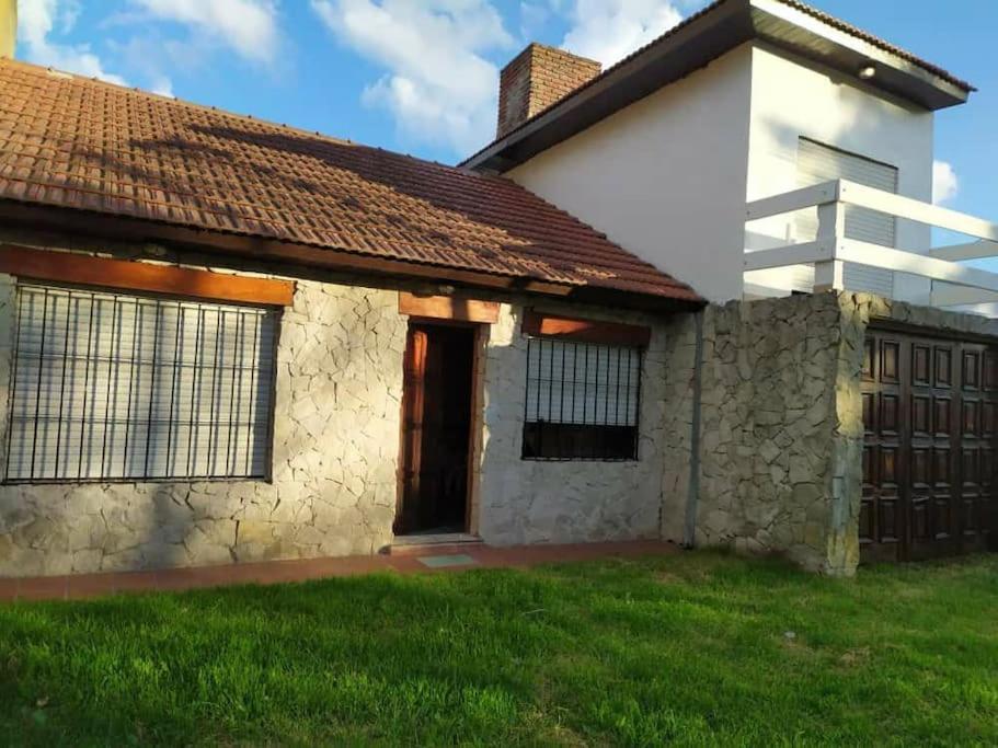 a house with a grass yard next to a building at Casa Chalet Lamar alojamiento entero in Santa Clara del Mar