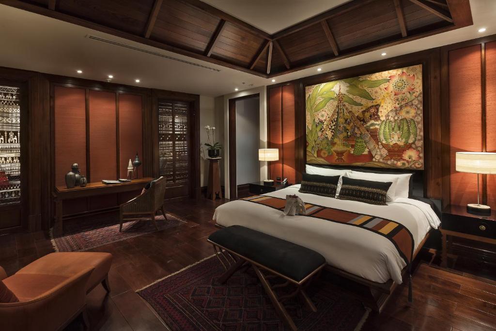 A richly furnished bedroom with a king-size bed, work desk and Thai-inspired artwork.
