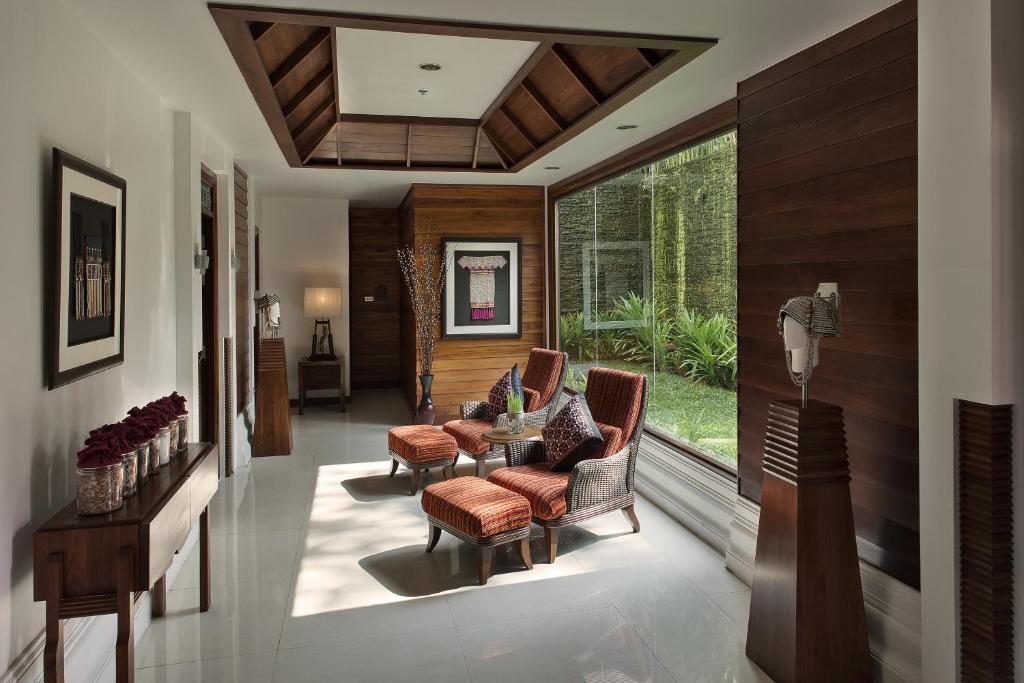 A bright indoor sitting area with upholstered chairs beside a garden-facing window.