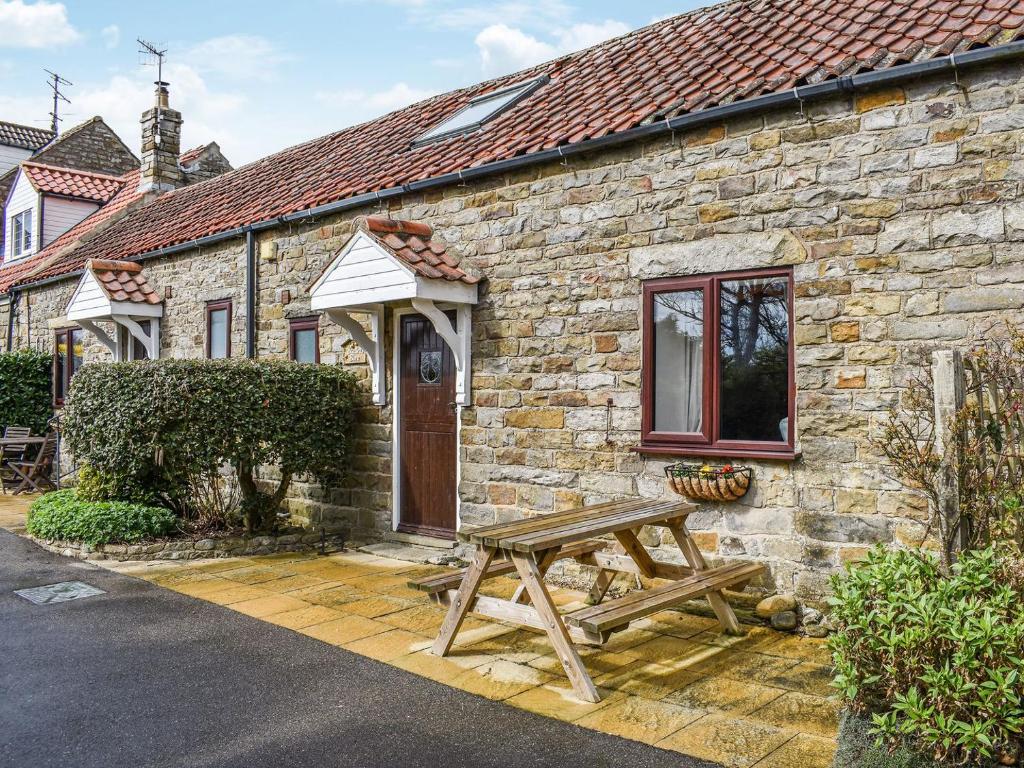 a wooden picnic table outside of a stone house at Bartletts Barn- Uk38276 in Cloughton