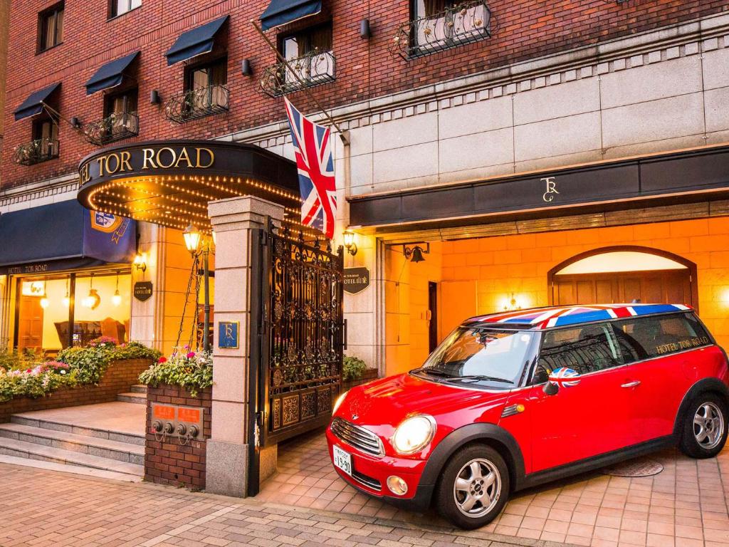 um pequeno carro vermelho estacionado em frente a um edifício em Kobe Tor Road Hotel Sanraku em Kobe