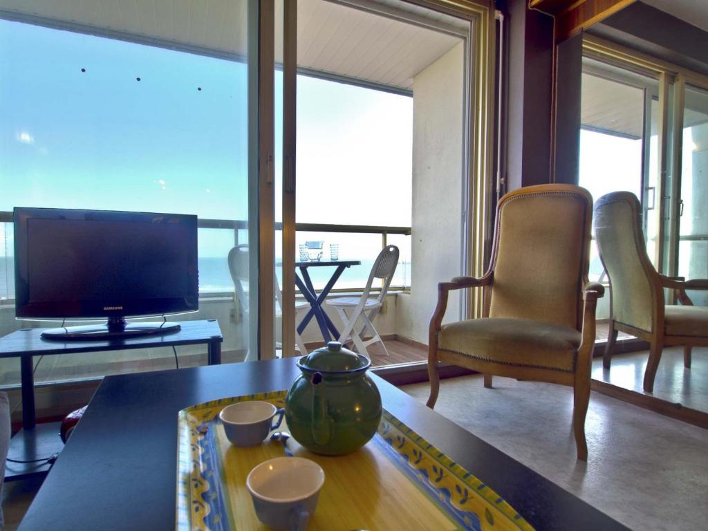 un salon avec une télévision et une table avec des tasses dans l'établissement Appartement avec Balcon - Plage à 150m, Parking - FR-1-92-639, à Les Sables-dʼOlonne