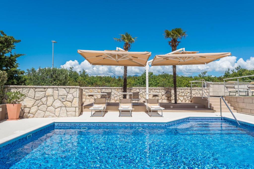 a swimming pool with umbrellas and chairs and a swimming pool at Apartments DYANA in Novalja