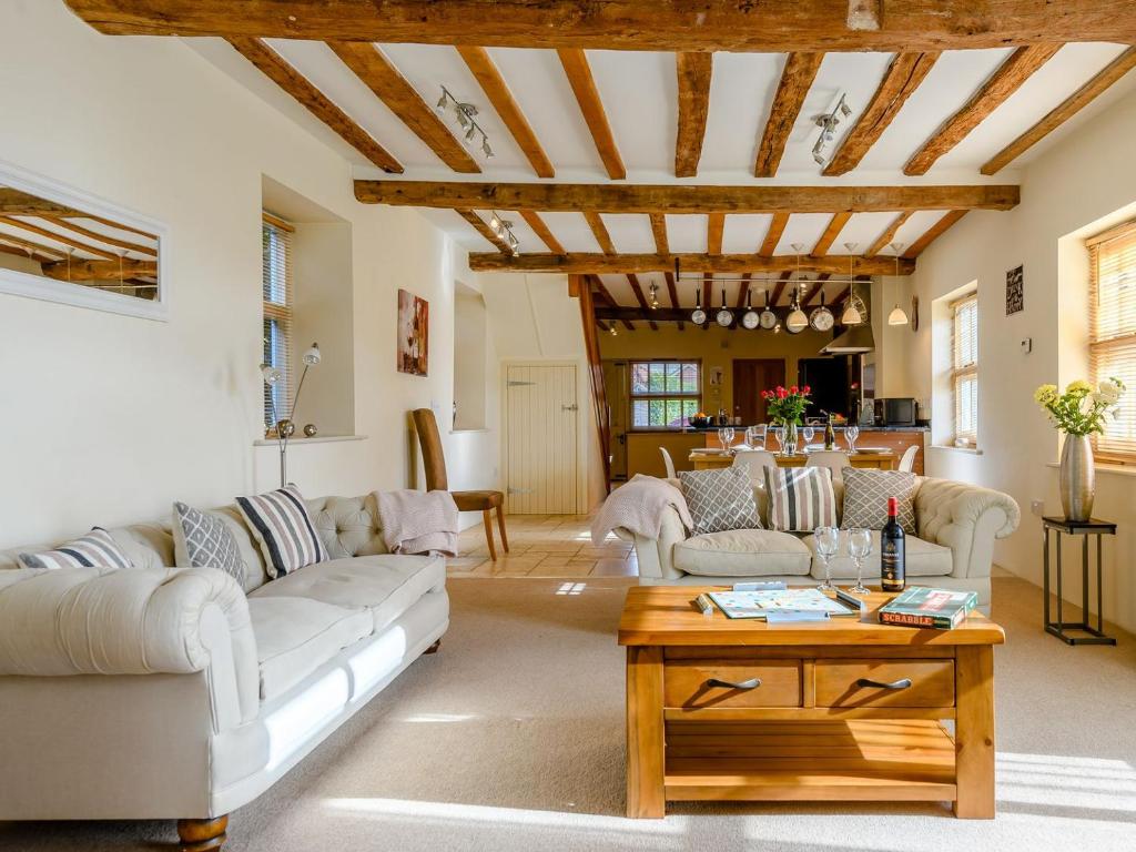 a living room with white furniture and a wooden ceiling at Laurel Barn in Ashwellthorpe
