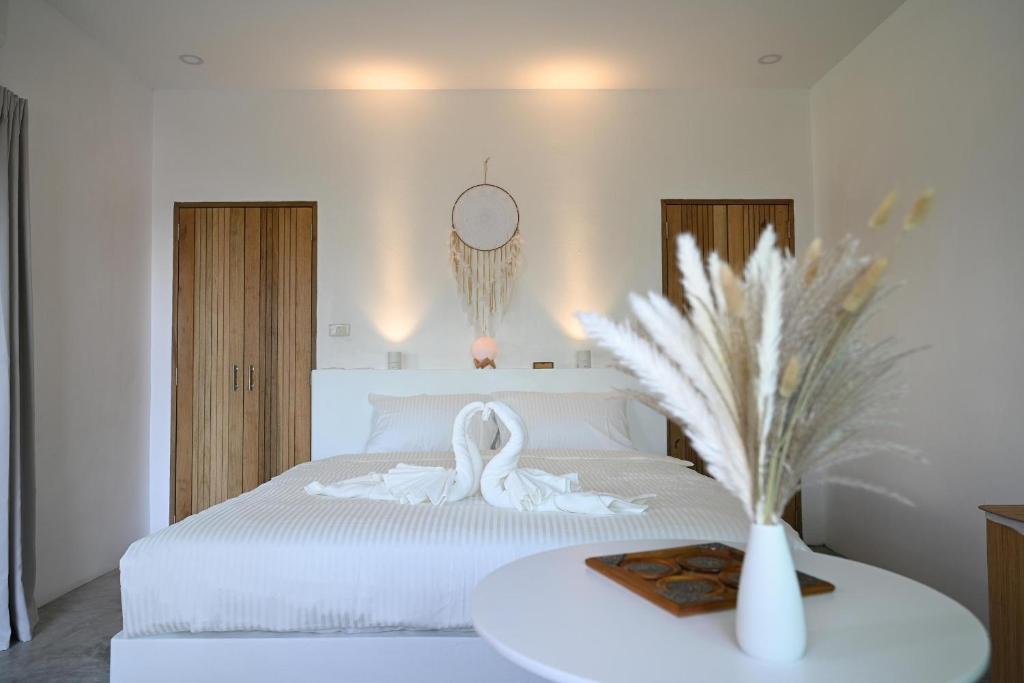 um quarto com uma cama branca com um cisne branco em Bao Village em Haad Yao