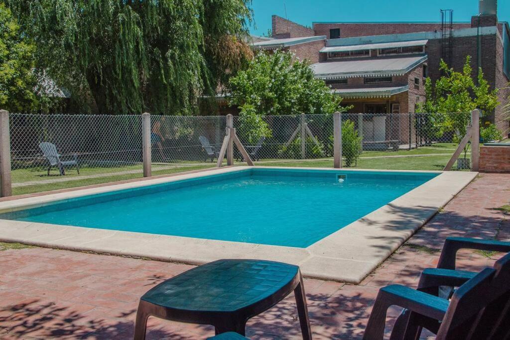 una piscina con una mesa y una silla junto a ella en Casa Departamento Funes Buena Vista Cochera Pileta en Funes