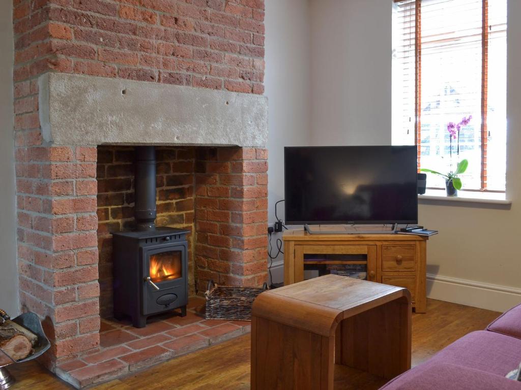 a living room with a brick fireplace and a television at Jubilee Cottage in Clifton