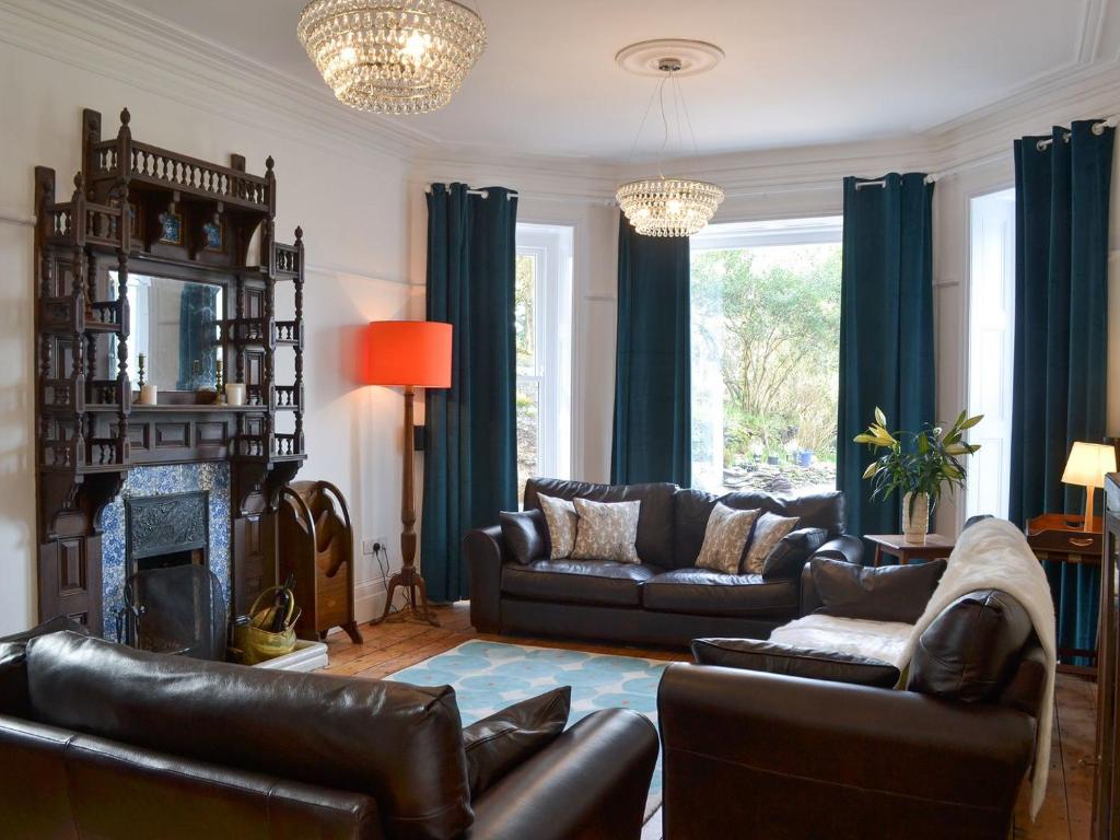 a living room with leather furniture and a fireplace at The Old Vicarage in Polperro