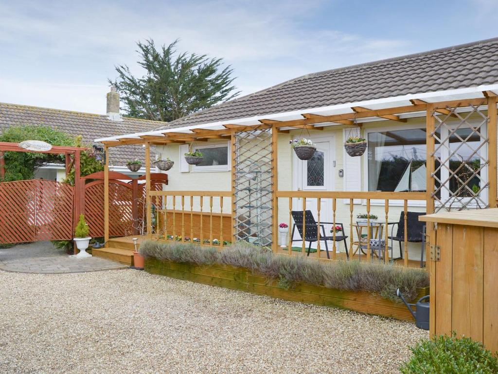 a house with a wooden deck with a table and chairs at Stable Cottage in Carisbrooke