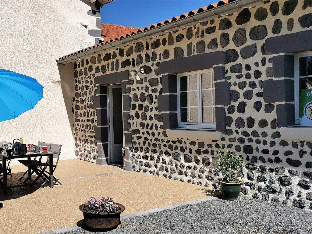 ein Gebäude mit einer Terrasse mit einem Tisch und einem Sonnenschirm in der Unterkunft Gîte Arlempdes, 5 pièces, 8 personnes - FR-1-582-107 in Arlempdes