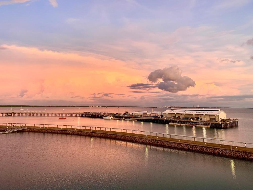 ein Pier auf dem Wasser mit wolkigem Himmel in der Unterkunft Absolute Waterfront - Tropical Sunrise Apartment Over The Water in Darwin