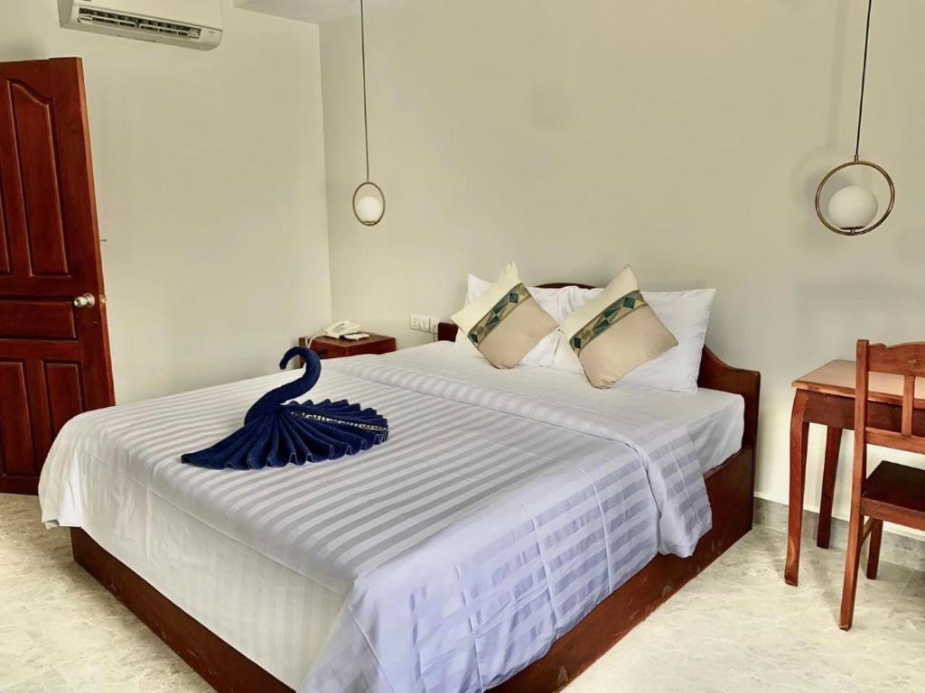 una camera da letto con un letto bianco e un asciugamano blu di Laluna Guesthouse a Siem Reap