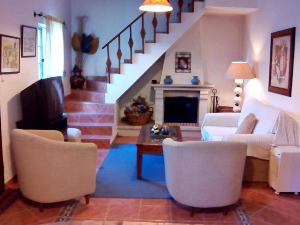 een woonkamer met een bank en stoelen en een trap bij Costa da Caparica Beach House in Costa da Caparica