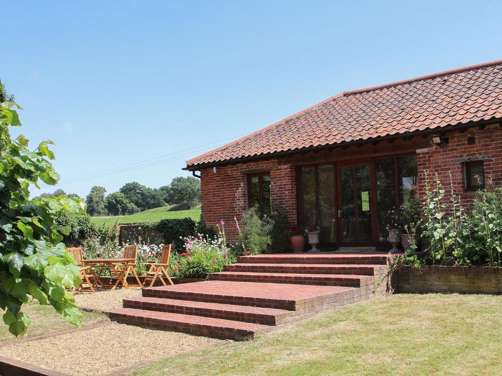 a brick house with stairs leading to a patio at Elm Tree Barn in Felmingham